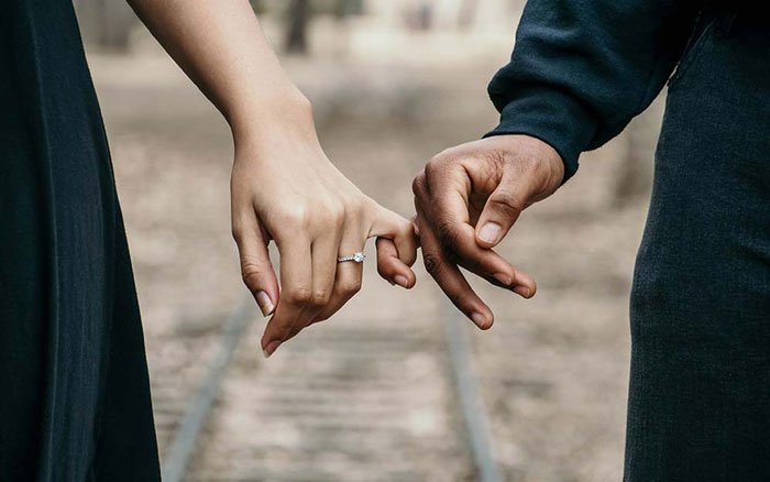 Married couple holding each other finger