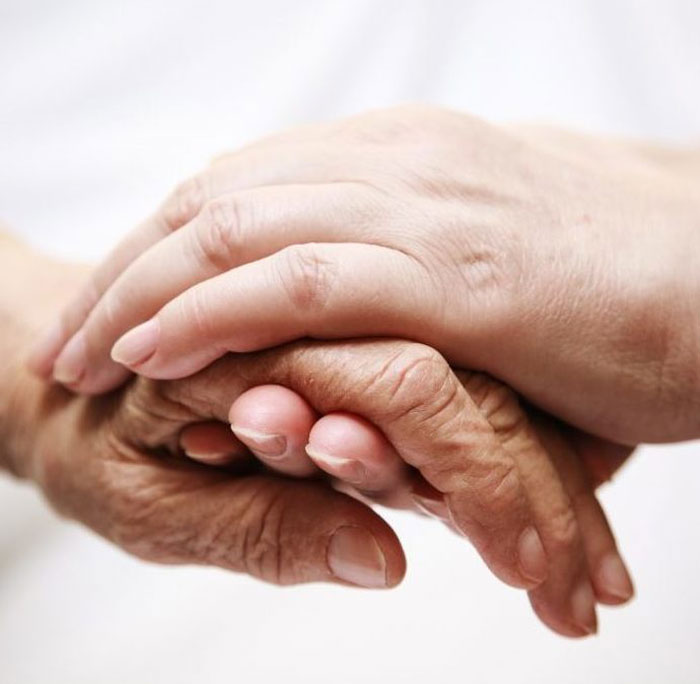 A man holds the hand of a senior citizen.